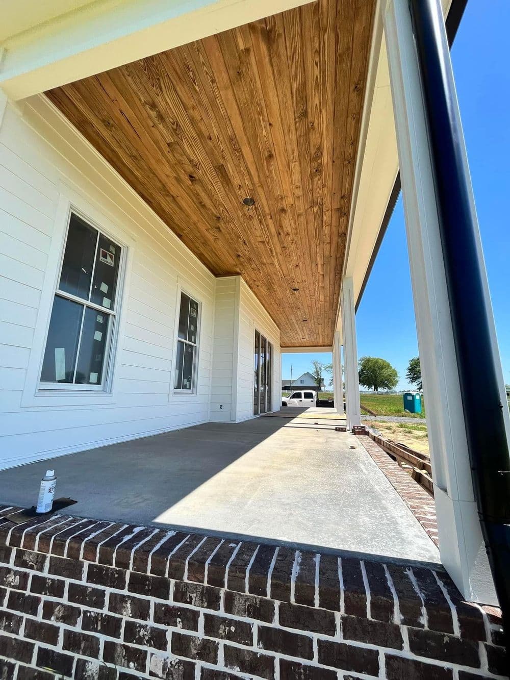 Newly constructed home exterior showcasing a wooden ceiling and brick foundation.