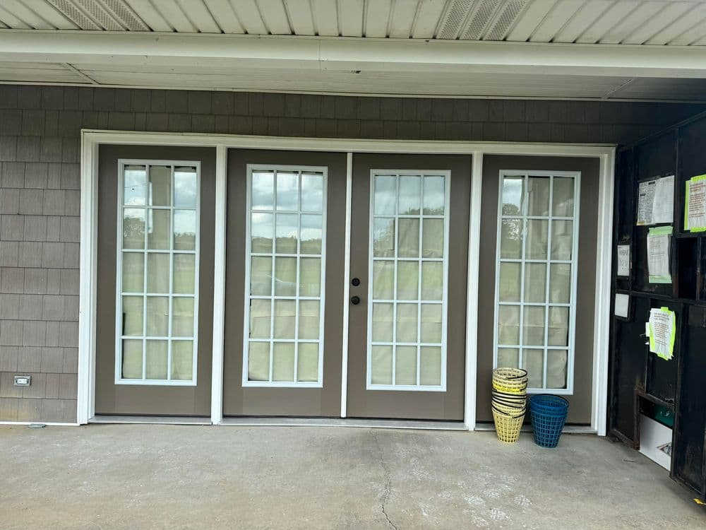Three modern double French doors with large windows, flanked by colorful baskets on a porch.